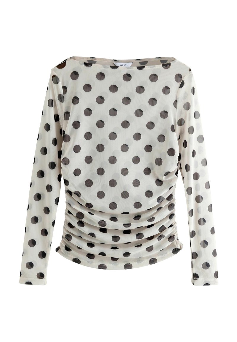 Langærmet top i transparent stof med sorte prikker på en lys baggrund, der har et sammensnøret design ved taljen.