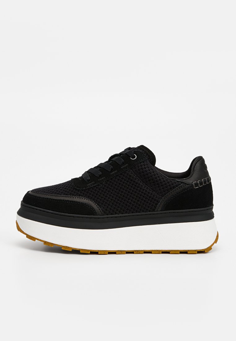 Czarny sneaker z siateczkowym i zamszowym wierzchem, płaskimi sznurowadłami, grubą białą platformą oraz brązową gumową podeszwą z bieżnikiem. Podkreślony eleganckimi detalami wzorniczymi.