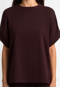 Burgundy oversized top made of soft fabric, featuring a round neckline and short sleeves with a relaxed fit and smooth texture.