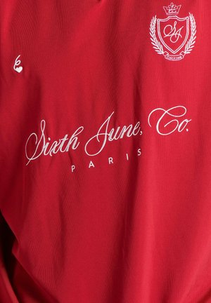 Red cotton T-shirt featuring white embroidered text "Sixth June, Co. PARIS" and a logo with a crown and laurel design.