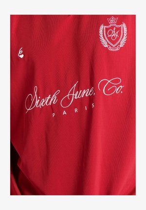 Rød bomulds T-shirt med hvid broderet tekst "Sixth June, Co. PARIS" og et logo med en krone og laurbærdesign.