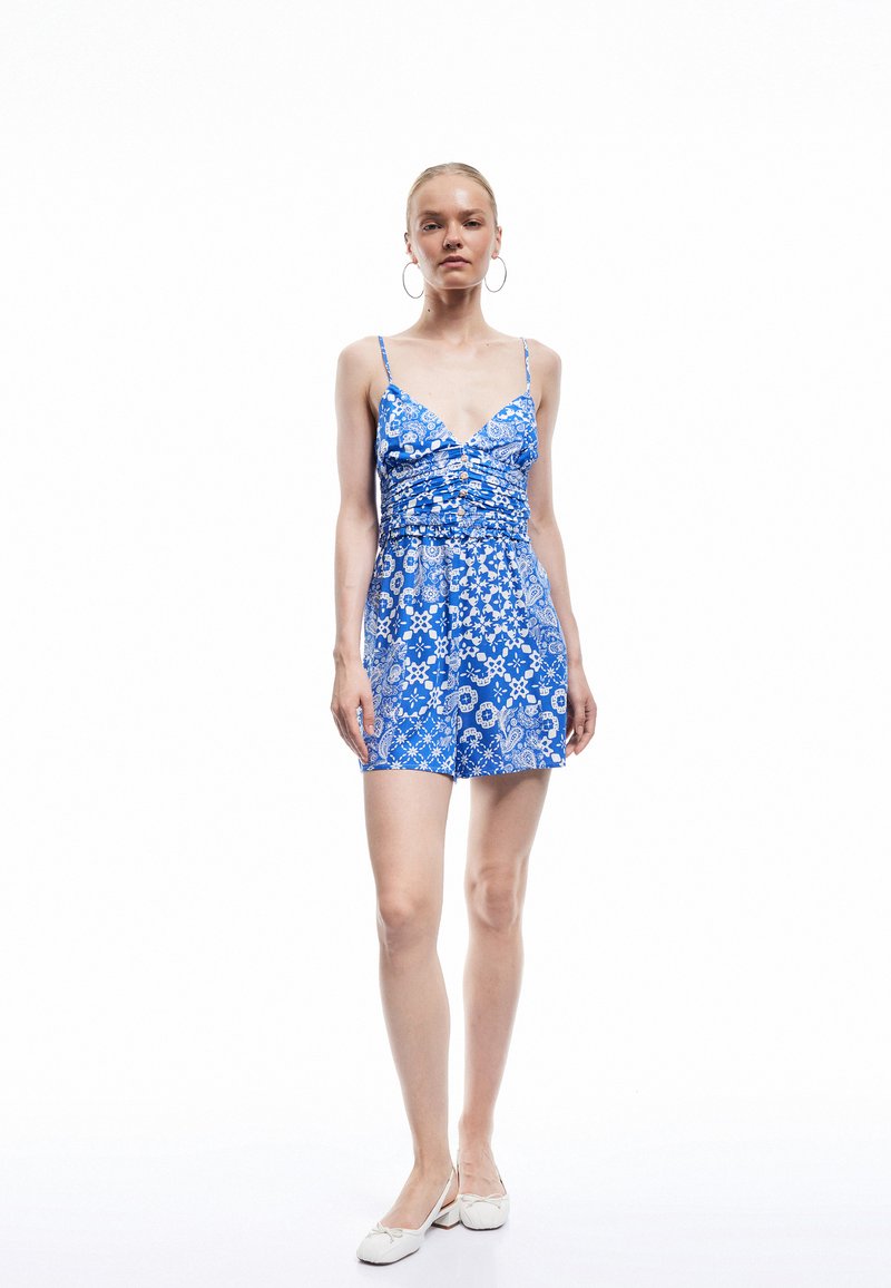Blauwe bloemenprint rompertje met spaghettibandjes, gerimpelde lijf en elastische tailleband. Gladde stof met een speelse paisleyprint.