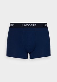 Sötétkék boxer alsónadrág puha szövetből, fekete derékpánttal, rajta fehér "LACOSTE" logóval. Testhez álló kialakítás zökkenőmentes elülső résszel.