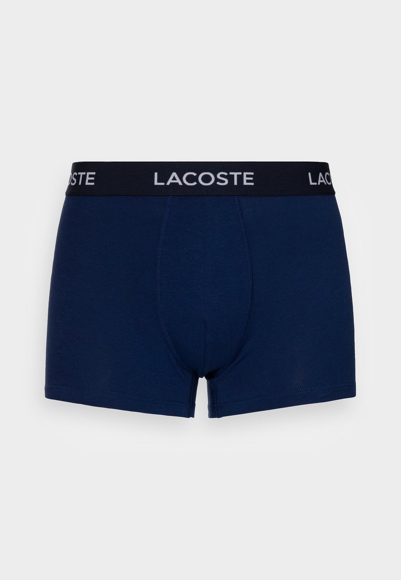 Donkerblauwe boxershorts van zacht materiaal, met een zwarte tailleband waarop het "LACOSTE" logo in het wit is gedrukt. Strak aansluitend ontwerp met een naadloze voorkant.