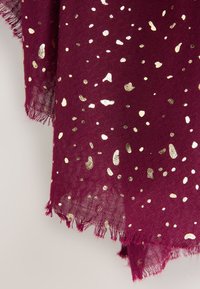 Burgunderroter Schal aus weichem Stoff mit einem verstreuten Muster aus Goldfolie, fransigen Kanten und einer strukturierten Oberfläche.