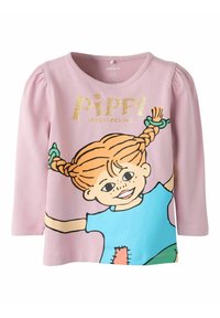 T-shirt rosa a maniche lunghe con un personaggio dei cartoni animati dai capelli arancioni in trecce, con la scritta "PIPPI" in oro luccicante e accenti blu e verdi colorati.