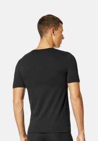 Camiseta negra ajustada con escote redondo y mangas cortas, hecha de material suave, que muestra una textura lisa y un diseño minimalista.