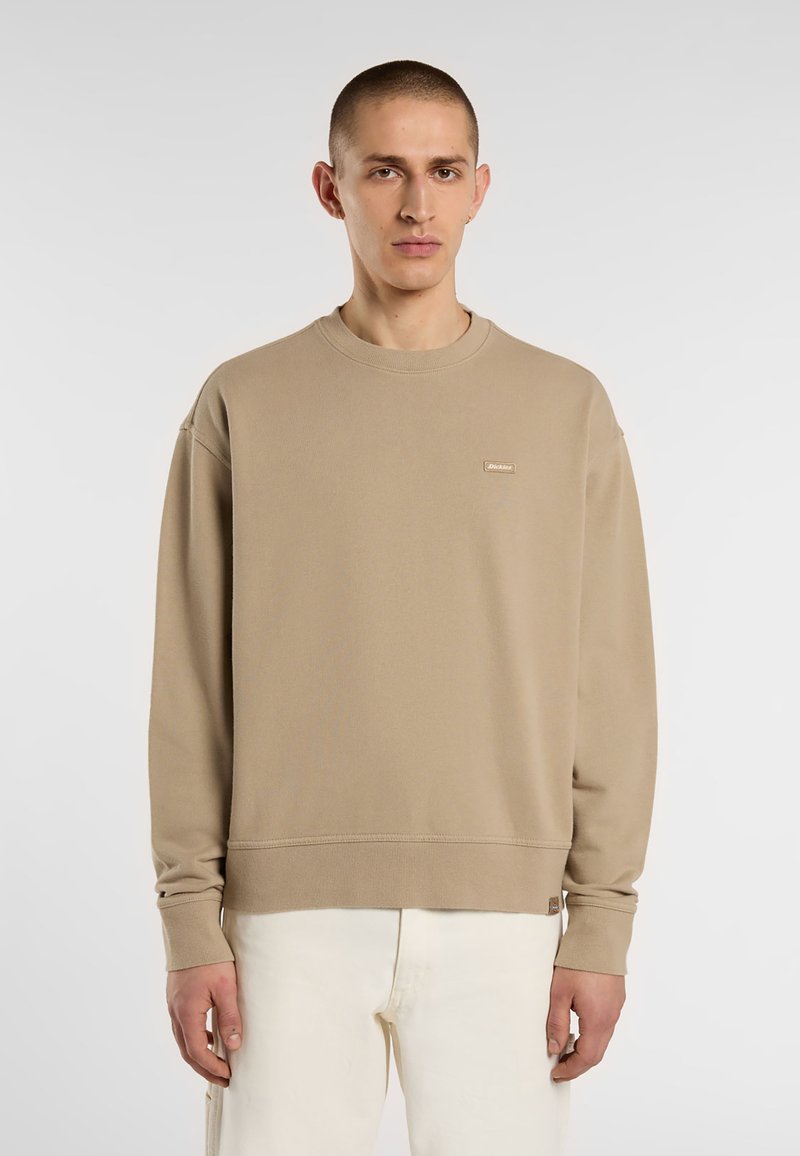 Beige sweatshirt met een ronde halslijn, lange mouwen en ribgebreide boorden. Beschikt over een klein logolabel op de borst en een relaxte pasvorm.