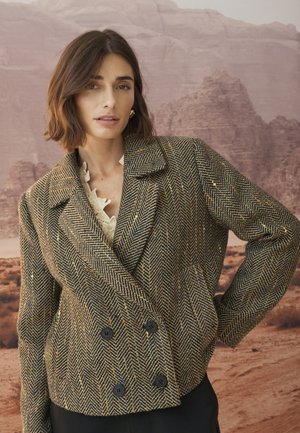 Braun-schwarz kariertes Blazer mit Hahnentrittmuster, doppelreihigem Design, Reverskragen und schwarzen Knöpfen mit strukturierter Oberfläche.