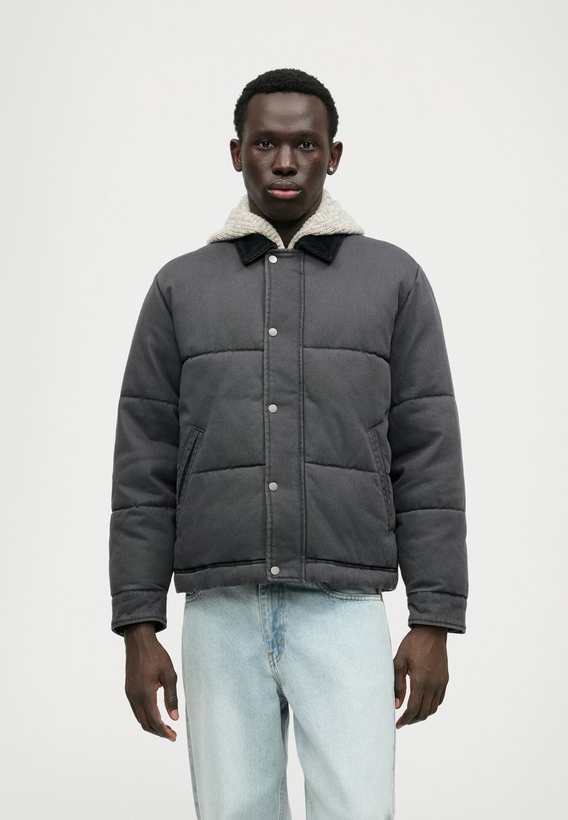 Jachetă gri căptușită cu guler căptușit cu sherpa, nasturi tip snap și buzunare laterale, asortată cu blugi de culoare albastru deschis.