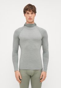Haut thermique ajusté à manches longues en tissu texturé gris clair, avec un col monté et des manches raglan, stylé avec des accents minimaux.