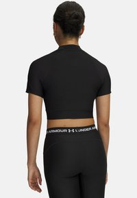 Μαύρο κοντό αθλητικό τοπ με κοντά μανίκια, υφασμάτινη υφή και ψηλό λαιμό, συνδυασμένο με μαύρο κολάν που διαθέτει λευκή μέση με λογότυπο.