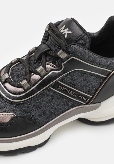 Sneaker noire et gris métallique avec un tissu texturé, un détail de logo, des accents contrastants et un design de semelle épaisse. Dispose d'une fermeture à lacets.