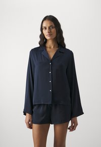 Navy satin sovsets med en långärmad skjorta med knappar och krage samt matchande shorts, slät textur med minimal detaljering.