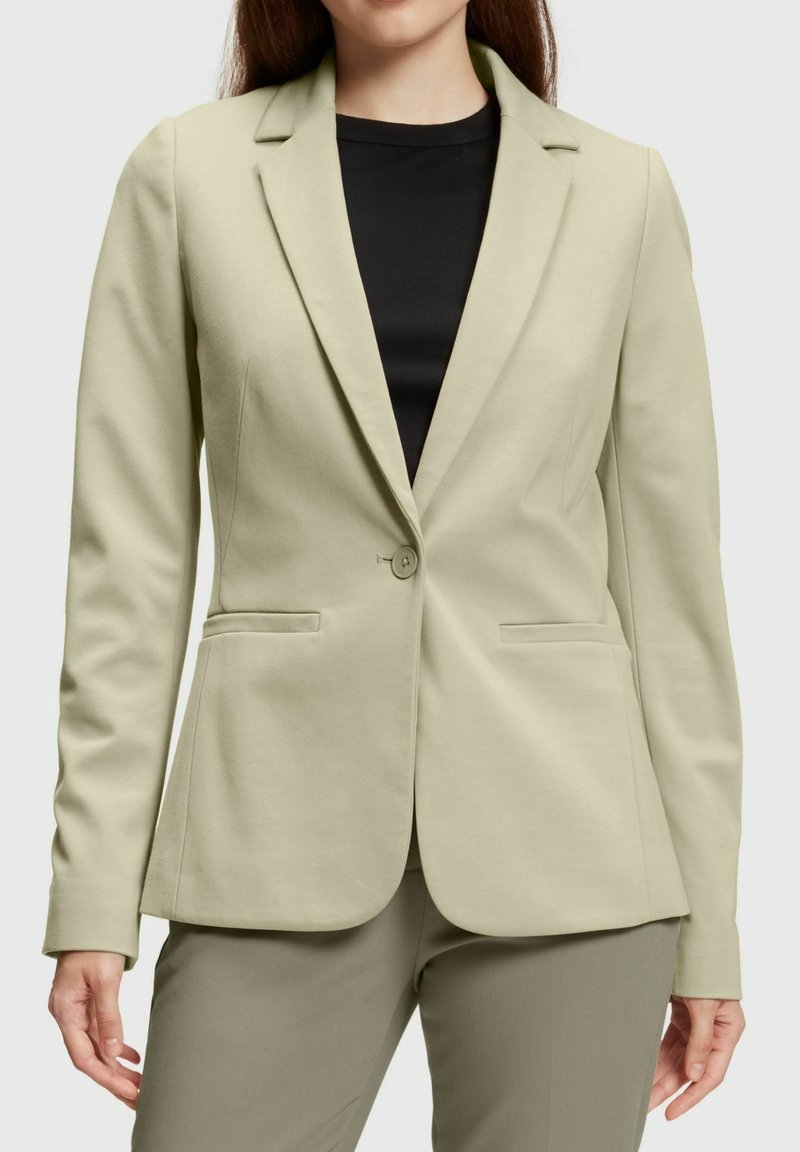 Blazer ajustado verde claro de tela suave, con solapas de muesca, cierre de botón único y dos bolsillos frontales.
