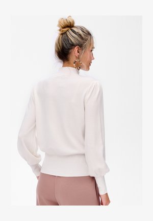 Cremfarbener Pullover mit langen, puffigen Ärmeln und geripptem Saum. Leichter Stoff mit glatter Textur und hohem Kragen.