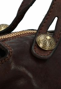 Bruine leren handtas met een messing rits, decoratieve stiksels en ronde reliëf hardware accenten op de handvatten.