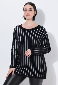 Schwarz-weißer gestreifter Pullover mit weitem Ausschnitt, langen Ärmeln und einem lockeren Schnitt. Das Material scheint gestrickt zu sein und hat eine weiche Textur.