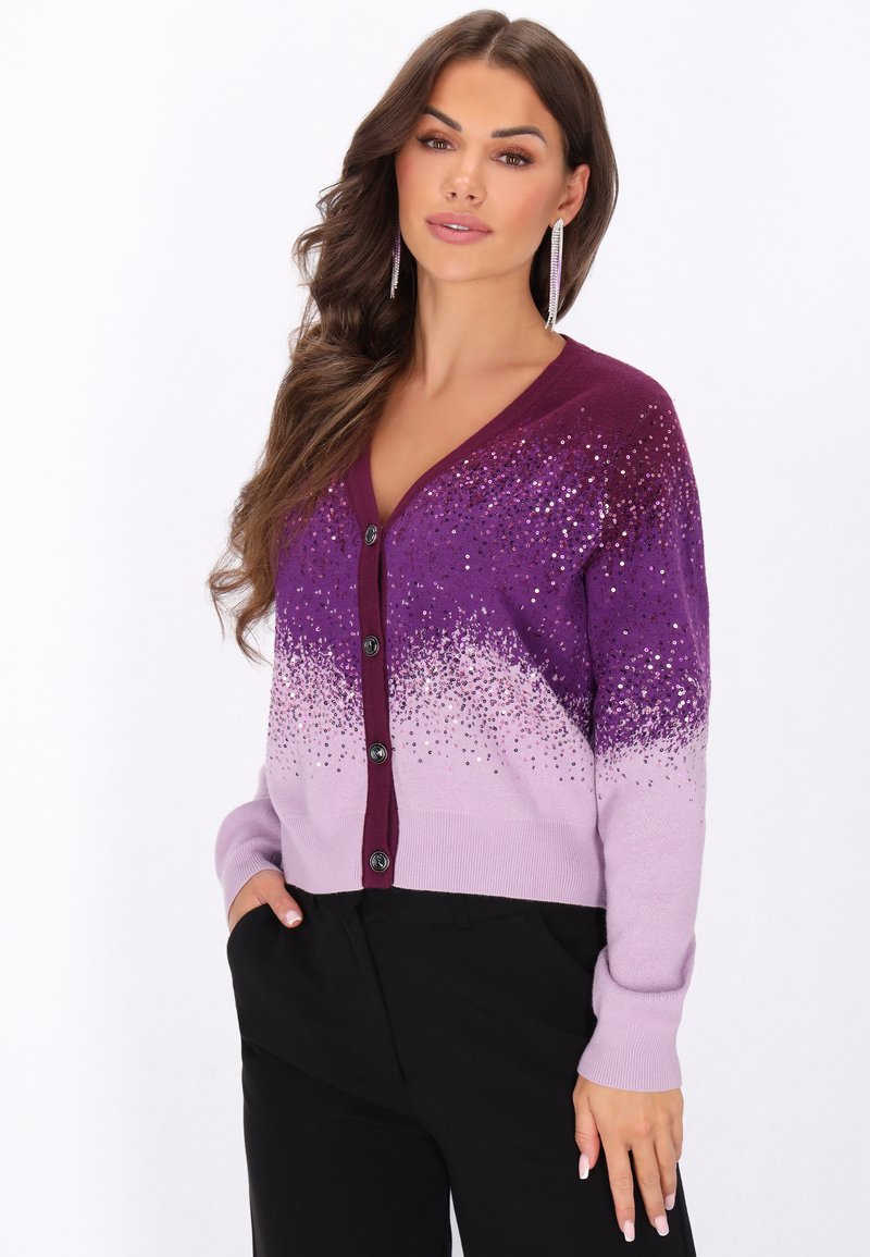 Cardigan gradient violet cu decolteu în V, nasturi și detalii strălucitoare. Material tricotat moale cu manșete și tiv ondulat, asortat cu pantaloni negri.