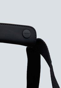 Prodotto nero con una cinturino in similpelle liscia caratterizzato da un logo circolare "JACKIT" e una sezione in tessuto elasticizzato per una vestibilità confortevole.