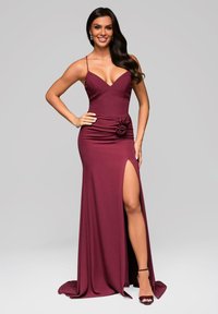 Vestito da sera bordeaux con un corpetto aderente, spalline sottili, uno spacco laterale e un'applicazione floreale in vita realizzata in tessuto morbido.