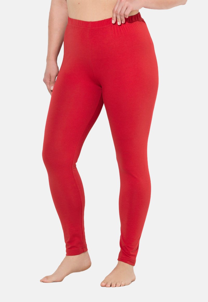 Leggings rossi realizzati in tessuto elasticizzato, con una cintura elastica e un design aderente che si estende fino alle caviglie. Texture liscia.