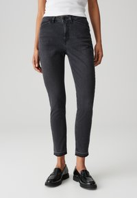 Jean skinny noirs à taille haute, avec une texture en denim lisse, un design à cinq poches et des détails de couture subtils.