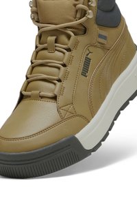 Bruna läder hög-top sneakers med grå detaljer, texturerad ovandel, framträdande snörningssystem och robust gummisula med ett uttalat mönster.