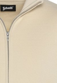 Felpa zip-up beige con finitura a maglia testurizzata; presenta una cerniera argentata e un'etichetta con il marchio all'interno del colletto.