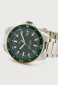 Men's analog watch with a green dial, gold accents, and silver stainless steel band. Features date window and luminescent hour markers.