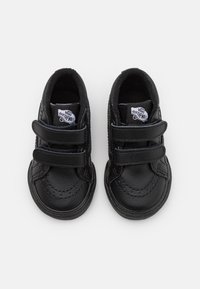Zwarte peuter Vans sneakers met twee klittenbandsluitingen en "Vans Off The Wall" logo's op de tongen, bekeken vanuit boven op een witte achtergrond.