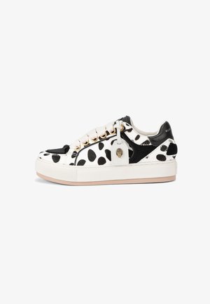 Baskets blanches avec texture tachetée noire et brune, ornées de détails noirs, de ferrures dorées, d'un bout texturé et d'une semelle en caoutchouc beige.