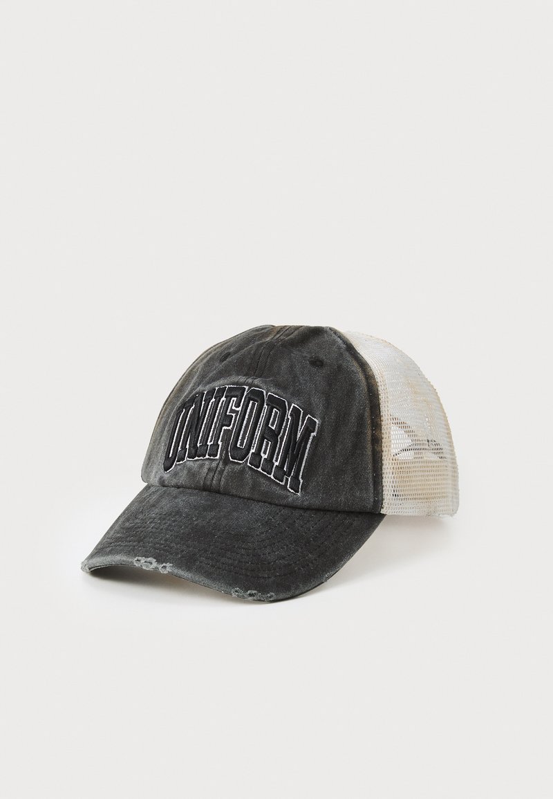 Casquette noire en tissu usé, avec un dos en filet et le mot "UNIFORME" brodé sur le devant. Visière courbée avec un léger degré d'usure.