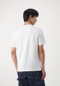 Witte katoenen t-shirt met korte mouwen, ronde halslijn en een gladde textuur; heeft een gestikte zoom en een relaxed fit.