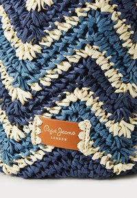 Borsa intrecciata in paglia con un motivo a zigzag blu e crema, dotata di un'etichetta in pelle color cammello con la scritta "Pepe Jeans London" impressa.