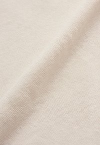 Tissu en coton beige clair avec un tissage fin et texturé. La surface est lisse avec une légère brillance, présentant un motif uniforme.