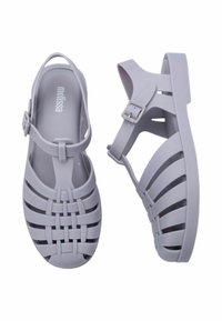 Sandali di gomma viola chiaro con design intrecciato e cinturino regolabile, dotati di suola piatta e ritagli laterali per una migliore traspirabilità.