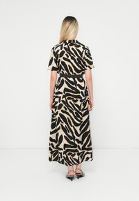 Maxi dress with short sleeves in a beige fabric featuring a black and gold abstract animal print. Designed with a fitted waist and flared skirt.