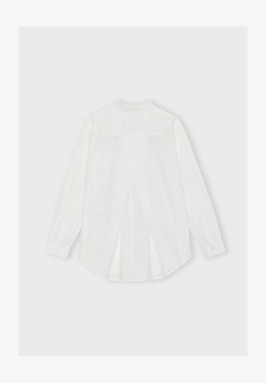 Bela srajca z dolgimi rokavi z visokim napelem na hrbtu, hrbtnim pregibom, gumbnimi manšetami in ukrivljenim robom. Gladka tekstura tkanine.