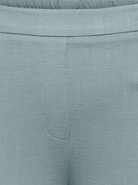 Gros plan sur un pantalon en tissu bleu clair texturé avec une taille élastique et des détails de coutures sur le devant.