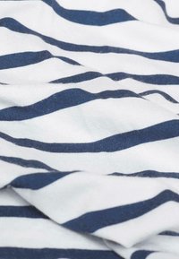 Gestreifter Stoff mit abwechselnd dunkelblauen und weißen gewellten Streifen. Sanfte Textur, leichtes Material und sanfte Falten sichtbar.