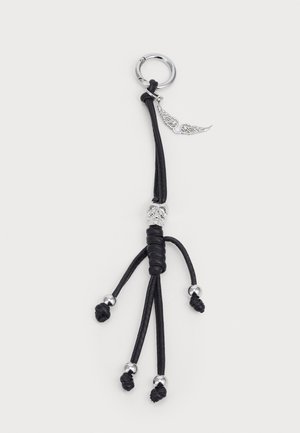 Porte-clés en cuir noir avec un design de figure humaine, présentant des accents métalliques et des nœuds aux membres, attaché à un anneau circulaire en argent.