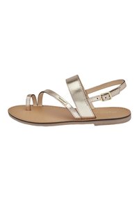 Sandalo piatto oro metallico con due cinturini diagonali, design open toe e cinturino alla caviglia regolabile. Sottopiede in pelle liscia. Stile minimalista.