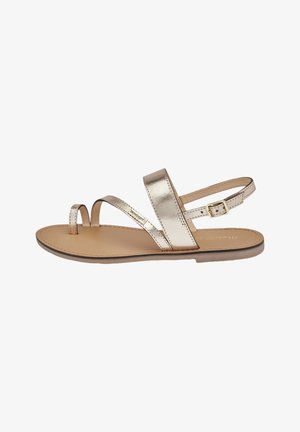 Metallic guld flad sandal med to diagonale remme, åben tå-design og justerbar ankelrem. Glat læder indersål. Minimalistisk stil.