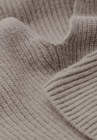 Weicher, gerippter Strickstoff in hellem Beige mit einer strukturierten Oberfläche, die abwechselnd schmale und breite Streifen zeigt.