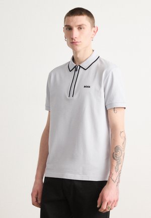Svetlošedé polo tričko s čiernym zipsom, kontrastným golierom a malým logom "BOSS" na hrudi. Krátke rukávy a hladká textúra.