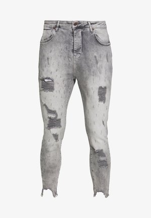 Jeans skinny grigi usurati con toppe strappate su cosce e ginocchia, orli sfrangiati e design classico a cinque tasche.