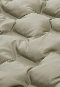 Opgevuld matras met een zachte, lichtbeige stofbedekking. Heeft tufted secties die een gestructureerd oppervlak creëren met een gladde afwerking.