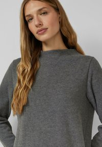 Grijze trui met een hoge hals, gemaakt van een zachte, gestructureerde stof. Lange mouwen en een losse pasvorm, zonder zichtbare patronen of hardwaredetails.