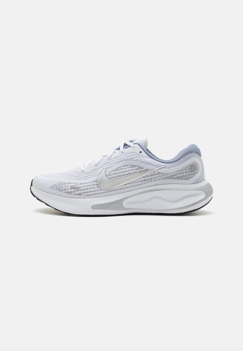 White athletic shoes with a mesh upper, gray accents, and silver logo. Rounded shape with cushioned sole and textured detailing on the sides.